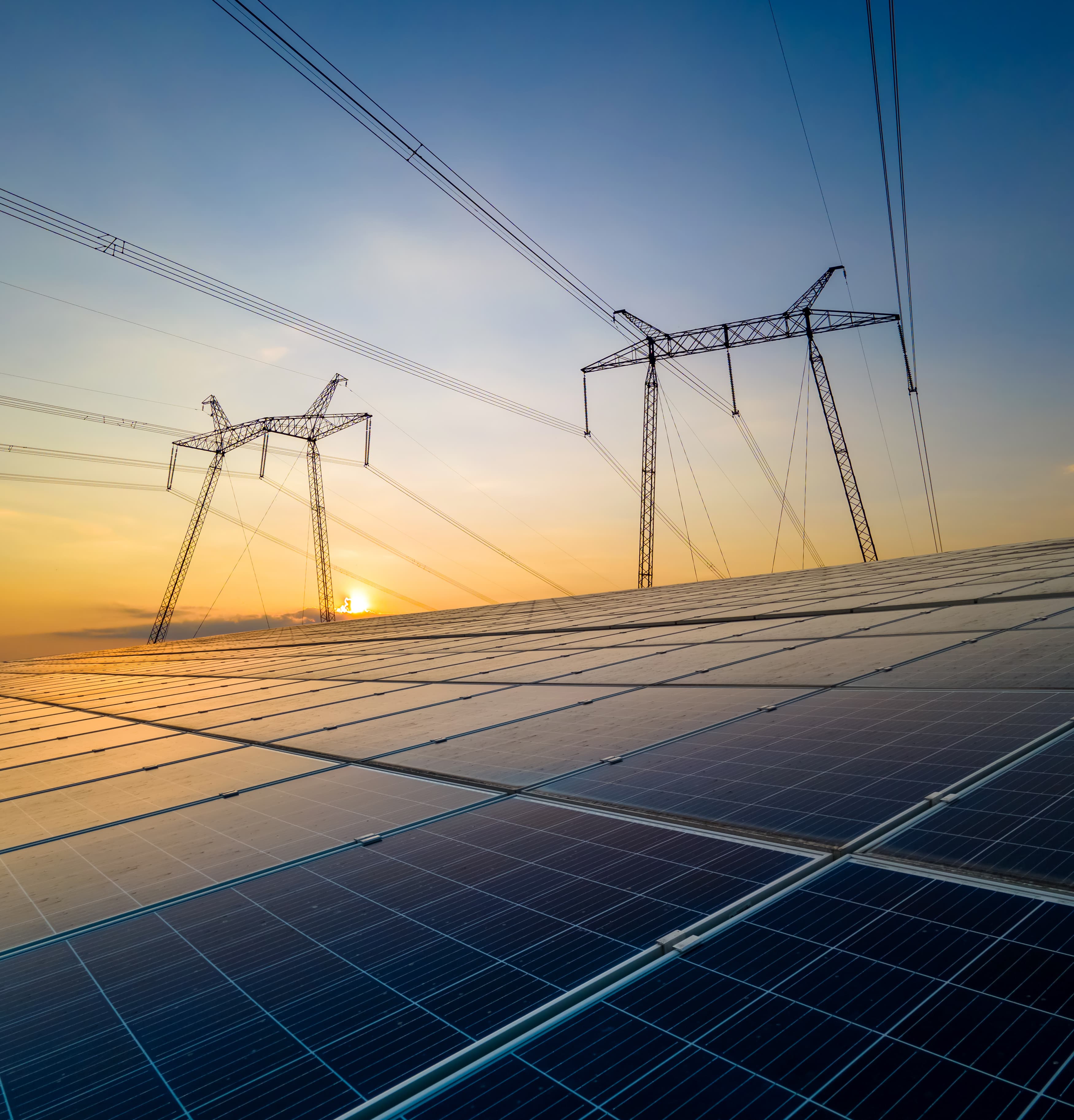 Solar panels and power lines at sunset